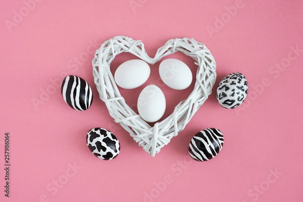 Obraz Easter eggs painted like zebra, cow, snow leopard. Three white eggs inside a white heart on pink background. Top view.