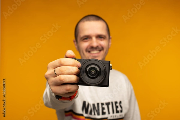Obraz Photographer man holding mirorrless camera in his hand