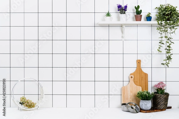Fototapeta Various kinds of kitchen tools arranged on the white table. And tidy flower pots are placed neatly on the shelf.
