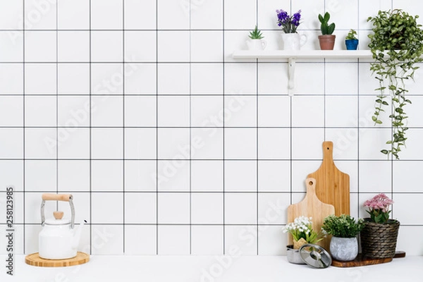 Fototapeta Various kinds of kitchen tools arranged on the white table. And tidy flower pots are placed neatly on the shelf.