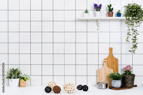 Fototapeta Various kinds of kitchen tools arranged on the white table. And tidy flower pots are placed neatly on the shelf.