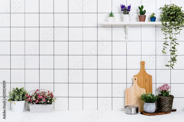 Fototapeta Various kinds of kitchen tools arranged on the white table. And tidy flower pots are placed neatly on the shelf.