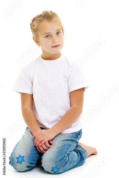 Obraz A little girl is sitting on the floor in a clean white T-shirt.
