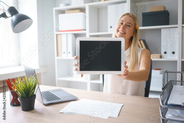 Obraz young beautiful woman work on tablet hold show screen sit at table in office smile