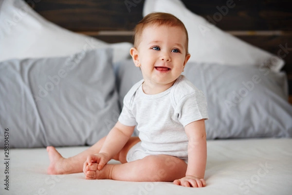 Obraz Smiling baby sitting on bed