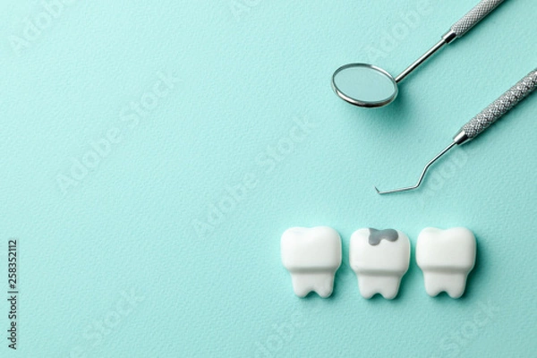 Obraz Healthy white teeth and tooth with caries on green mint background  and dentist tools mirror, hook. Copy space for text.