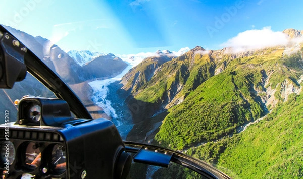 Fototapeta View from the cockpit of a helicopter as it flies over the Fox Glacier on New Zealand's south island.