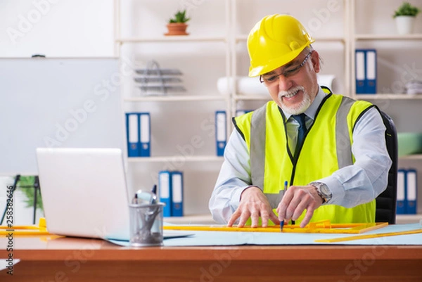 Fototapeta Aged construction engineer working in the office