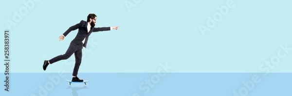 Fototapeta bearded businessman riding a skateboard, man pointing finger on copy space, panoramic image