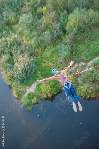 Fototapeta Extreme jump from the bridge. The man jumps surprisingly quickly in bungee jumping at Sky Park explores extreme fun. Bungee in the canyon.