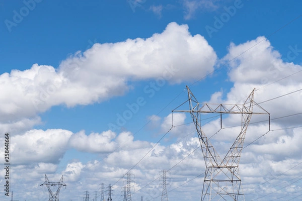 Obraz Large high tension power lines with cables and structures showing on a parlty cloudy and sunny day with blue skies