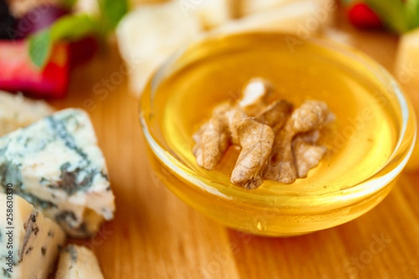 Fototapeta dorblu slices close up. Cheese plate served with fruits, walnuts and honey. delicious snack on wooden platter