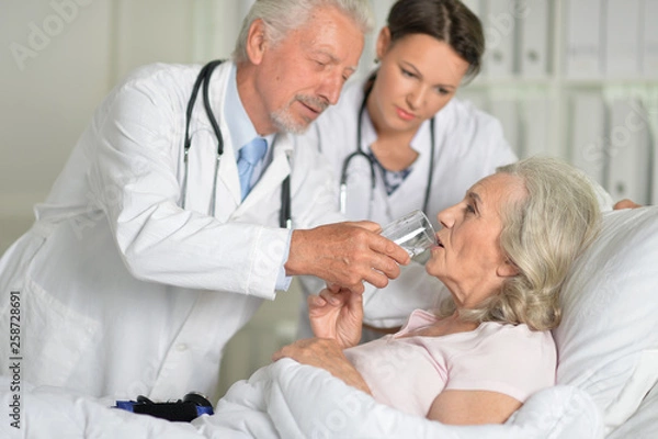 Fototapeta Portrait of two professional doctors inspecting patient