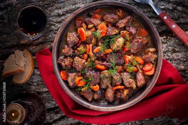 Obraz Stewed beef with carrots and onions in pottery, top view, horizontal