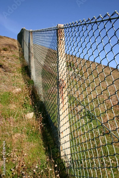 Fototapeta close view of a ong fence up a steep hill