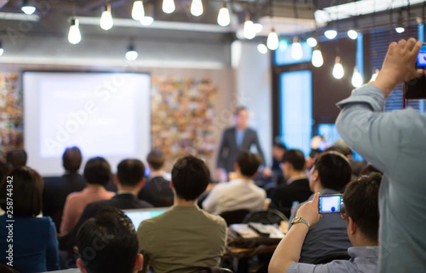 Fototapeta Conference Photo with Audience. Business Crowd and Executive Speaker on Stage. Business Presentation Presenter Speech at Meeting. Forum at Corporate Manager Event. Expert Seminar Lecture Conference.