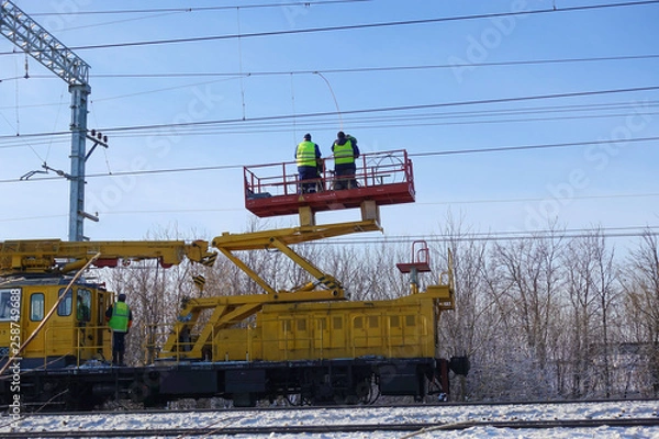 Fototapeta Special train with a landing crane for service and repair of electrical networks on the railway. Workers doing service work on electric lines over the rails