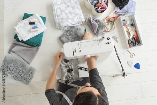 Fototapeta Tailor, fashion and seamstress concept - young female fashion designer in her showroom, top view