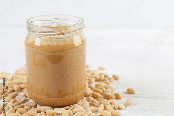 Obraz peanuts and peanut butter in a jar on the table