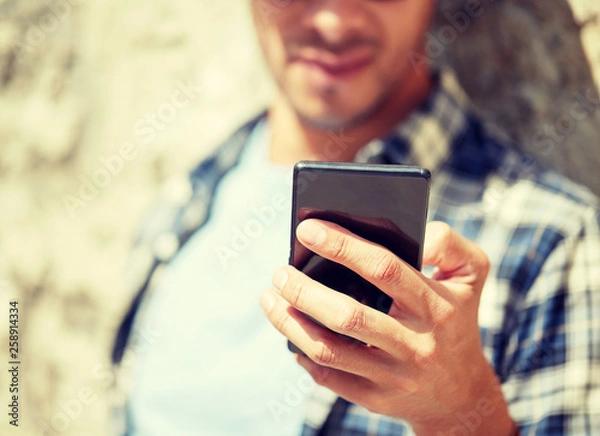Fototapeta technology, communication and people concept - close up of man with smartphone texting message outdoors