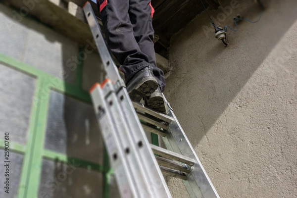 Fototapeta Texture, background, spring repairs, man uploaded on a folding ladder to repair the roof of an old rural house. Concept village.
