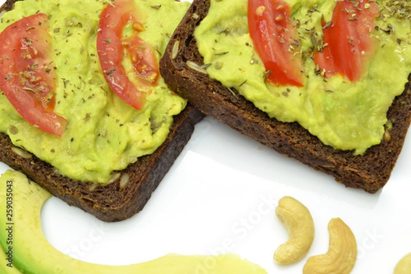 Fototapeta sandwich with avocado on a white plate nuts
