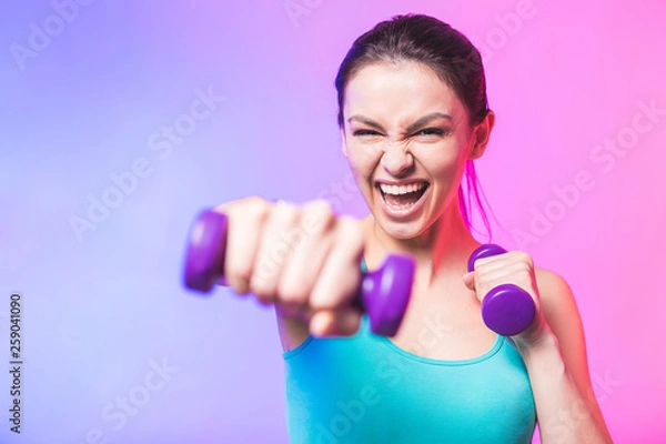 Fototapeta Close-up portret młodej atrakcyjnej szczęśliwej kobiety w strojach sportowych z pięknym uśmiechem trzymając hantle wagi robi ćwiczenia fitness na białym tle na białym tle w koncepcji zdrowego stylu życia