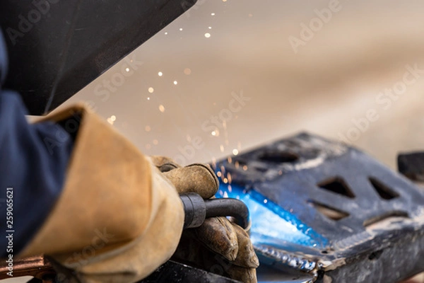 Obraz A mig welder is used to weld two pieces of metal steel together close up