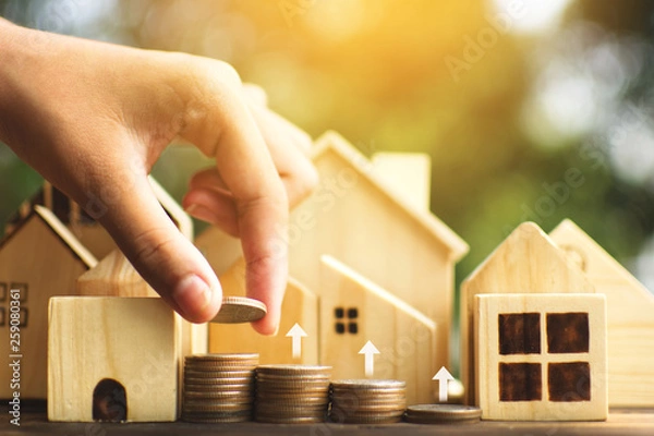 Obraz Female hands protection the little wood house model on plank and tree bokeh background, start to plan and saving money for residential .