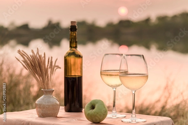Fototapeta A romantic dinner in summer on a beach at sunset with two glasses of white wine