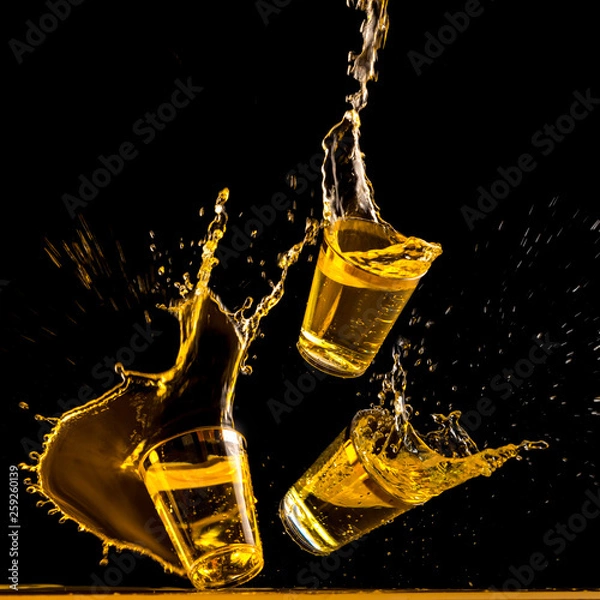 Obraz Three golden tequila shots crashing down and splashing