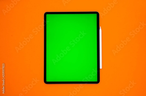 Fototapeta new tablet on a Orange background with a keyboard and pen, and green screen top view