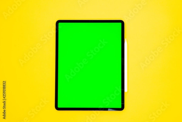 Fototapeta new tablet on a Yellow background with a keyboard and pen, and green screen top view