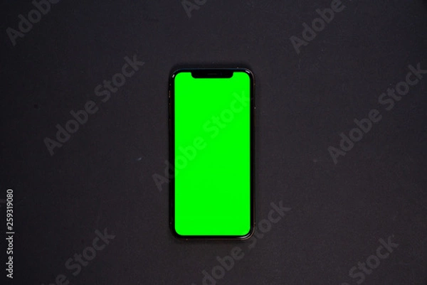 Fototapeta iPhone XS, smartphone, green screen on Black background top view