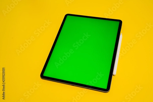 Fototapeta new iPad, tablet on a Yellow background with a keyboard and pen, and green screen top view
