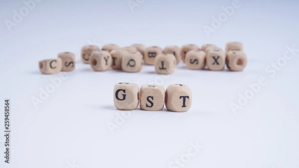 Fototapeta GST inscription on wooden alphabet over white background with selective focus