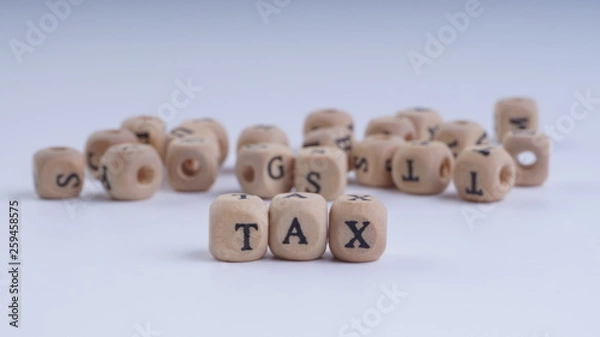 Fototapeta TAX inscription on wooden alphabet over white background with selective focus