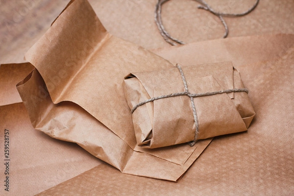Fototapeta Brown paper craft package with hemp cord. Packaging process. Mail packages.  Soft wrapped bundle parcel. Organic boxing. 