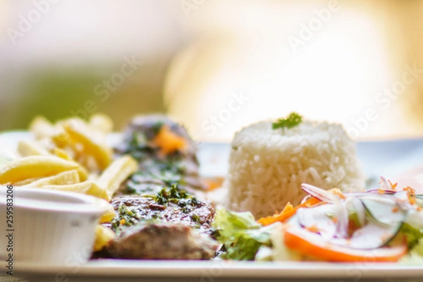 Fototapeta grilled beef steak served on plate withh rice, salad and frites. Selective focus photography