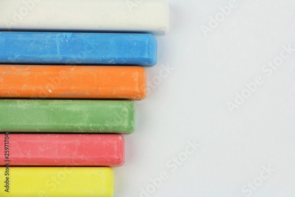 Fototapeta six colored children crayons on white background, on left side, blue red green yellow orange white, top view