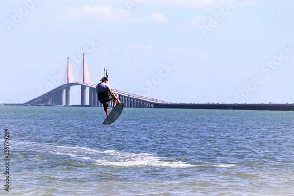 Obraz Kite surfer gaining air with a kite above as he attempts to jump the skyway bridge,