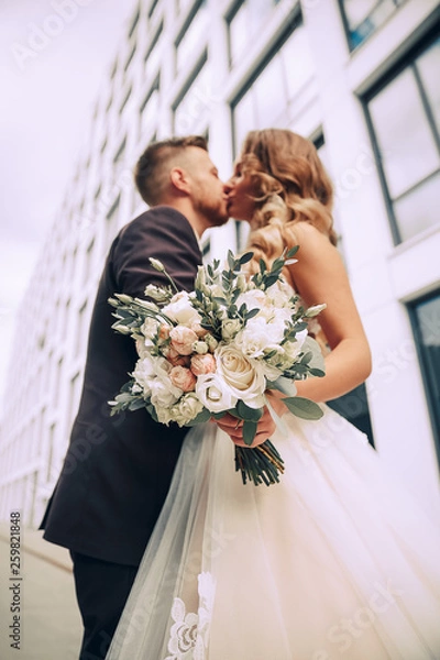 Obraz Couple in love on a walk in the city.The couple on the background of a modern building.Wedding photo