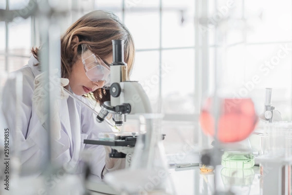 Obraz A young Asian woman scientist working in laboratory with test tube microscope and solutions.