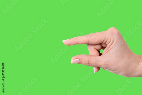 Fototapeta Closeup view of female hand forming gesture Little bit. Isolated on bright green chroma key background. Horizontal color photography.