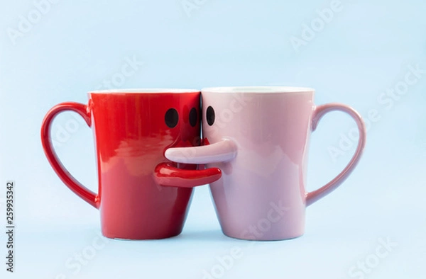Fototapeta Friday's happy word. Two cups of coffee on a blue background with a smile facing the mug, hugging each other. The concept of love and relationships. Creative colorful greeting card