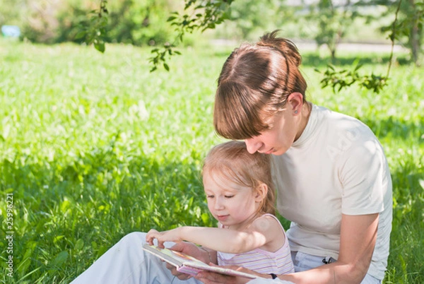 Obraz Mother and daughter sitting on the grass and looking book