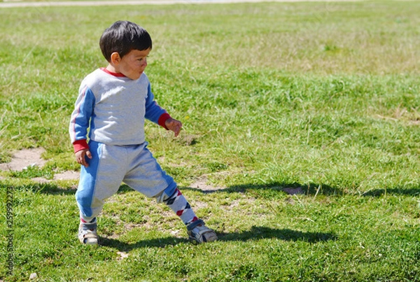 Fototapeta Funny little latin boy doing exercise outside.