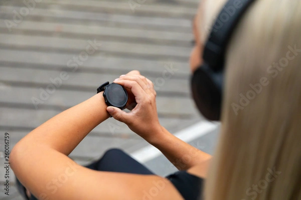 Obraz Female runner setting up the fitness smart watch for running