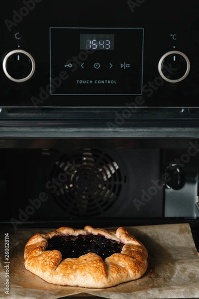 Fototapeta Closeup photo of galette with black currant baking in a oven