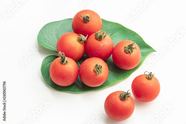 Fototapeta Close up tomatoes in green leaf on isolate white background.Selective focus red tomatoes.	